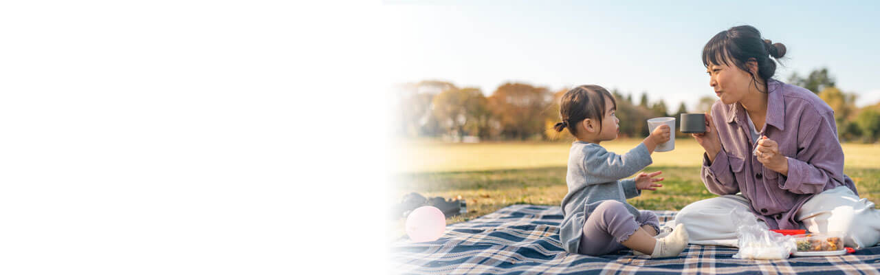 A mum and her young daughter enjoying a picnic in the park