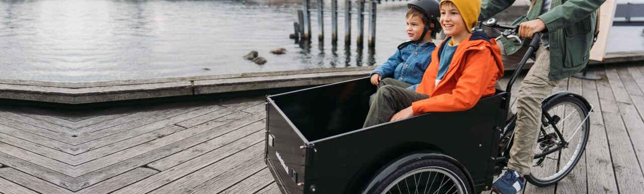 Two children enjoying a ride along the canal in a cargo bike.