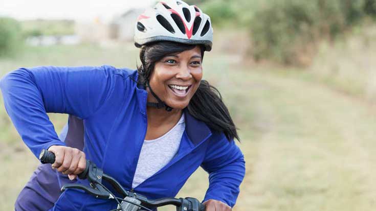 Smiling woman on bike in the countryside.