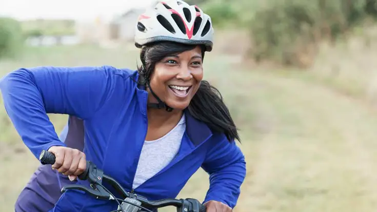 Smiling woman on bike in the countryside.
